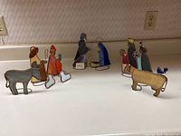 Full view of three sets of stained glass nativity figurines featuring various characters and animals.