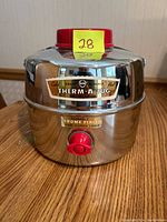 Front view of the vintage chrome finish Therm-A-Jug with red spigot and red lid showing branding labels.