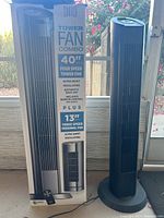 View of two Sunter 40 inch tower fans with box showing product details including four speed, ultra quiet, oscillating, automatic shut off, remote control and inclusion of 13 inch personal fan.