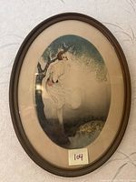 Front view of oval framed print showing woman by a pond with ducks and tree in background.