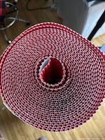 Close-up top view of the rolled red corrugated paper, showing internal layers and texture.