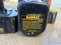 Close-up of battery label showing Dewalt DW9071 12.0V battery pack with safety warnings and usage instructions.