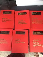 Top view overview of six red hardcover books in excellent condition with gold embossed Popular Mechanics logo and titles showing various DIY topics.