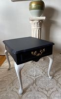 Full view of the refurbished solid oak side table showing black tabletop, white curved legs, and gold handle on drawer.