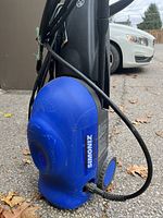 Blue Simoniz S1600 pressure washer main unit shown on pavement with cables visible