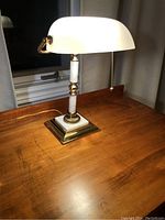 Lamp fully assembled on wooden table by window, lit to show working condition.