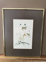 Full view of framed ink and watercolour artwork showing the two rams with curled horns, dark matte, and gold-tone frame.