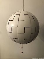Front view of white spherical pendant lamp showing segmented panels and pull chains for adjusting light.