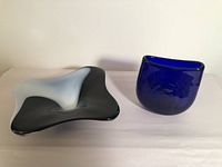 Photo showing both the black and white art glass bowl and the cobalt blue vase together on a white surface with neutral background