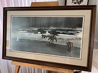 Framed print on easel showing full view of artwork featuring three bears by water with reflections, moody background