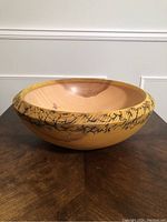 Front angled view of the round turned wooden bowl showing the light wood interior and pronounced black fractal burn pattern on the rim.