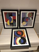 Three framed Sonia Delaunay prints displaying abstract geometric artwork with circular and angular shapes in vibrant colors.