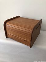 Photo of the teak tambour roll top box closed, showing the smooth teak wood grain and rounded edges.