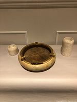 Full view of marble ashtray with brass accents accompanied by two marble candleholders on each side
