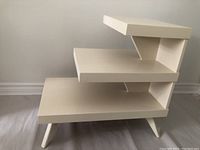 Side view of the vintage painted side table showing three stepped levels and angled support braces.