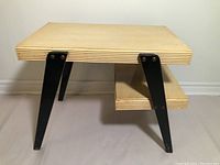 Front and left side view of the vintage side table showing plywood top with layered edges, black metal legs, and lower shelf.