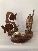 Front view of the fish mobile, fisherman carving, and brass-accented wood duck placed together on a surface