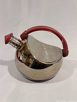 Front-side angled view showing kettle body, spout with red cap, and red handle.