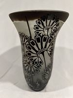 Front angle showing floral carved and etched design on gray and black glass vase with flared mouth