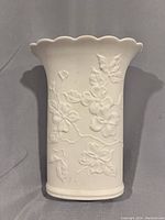 Front view of the vintage white porcelain vase showing embossed dogwood flower pattern and scalloped top edge.