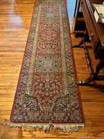 Full-length view of red floral wool runner rug on hardwood floor