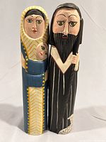 Front view of two hand carved and painted wood nativity figures from Bali, showing Mary holding baby Jesus and Joseph with staff.