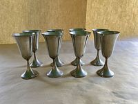 Group view of eight matching tulip-shaped goblets with fluted design, set in two rows against a brown background.