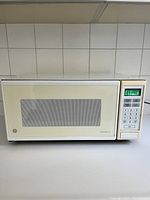 Closed view of white General Electric Spacemaker III microwave showing front with keypad, display, and windowed door.