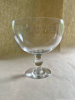 Clear glass pedestal fruit bowl shown upright on neutral background, showing overall shape and size.