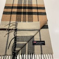 Folded scarf showing the pale tea background with black and cinnamon check pattern and fringed ends.