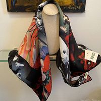 Full view of the multicolored silk scarf draped over a display stand showing floral and abstract patterns with attached Kenzo tags.