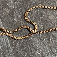 Close-up of square box chain links on a dark background