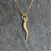 Pendant and upper portion of box chain displayed on dark slate background.