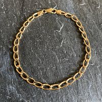 Full view of gold bracelet on dark surface.