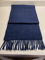 Dark blue/grey lambswool blend scarf folded to show texture and length with fringes.