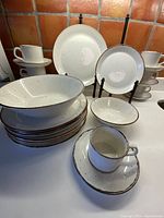 Full display of dinnerware set showing dinner plates, cups and saucers, cereal bowl, luncheon plate and large serving bowl.