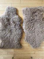 Overhead view of two taupe grey sheepskin rugs laid flat showing their natural shapes and texture.