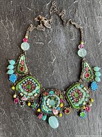 Full view of Ayala Bar handmade necklace laid flat showing five beaded panels connected by beaded chain on dark background