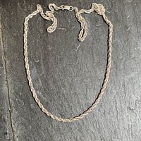 Full view of the sterling silver multi-link twisted rope chain necklace laid out flat on a dark surface.