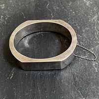 Top angle showing the chunky angular hinged sterling silver bracelet with safety chain attached to clasp.