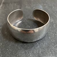 Front/top view of solid sterling silver cuff on dark background