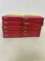 Stack of seven boxed rolls of Scotch 27 Glass Cloth Electrical Tape from side view showing product labeling.