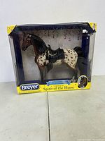 Front view of the packaged Breyer Spirit of the Horse model horse figurine showing the horse inside a damaged clear plastic packaging with a yellow corner protectors.