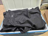 Photo showing several pairs of folded black Cintas pants inside the cooler.