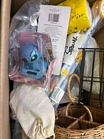 Photo showing the blue character figurine in packaging, drawstring cloth bag, woven baskets, kitchen utensil, and other wrapped items inside a large box.