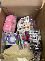 Box top view showing colorful plastic straws, pink plush item, clear containers, and assorted packaged goods.