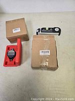 Overview of digital gauge in red case, digital dial indicator with bubble level, and two cardboard boxes.