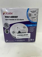 Front view of boxed Kidde Pro Series 120V Smoke and CO Alarm, showing packaging and branding.
