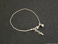 Photo of a silver bracelet laid flat showing the chain and clasp against a dark background.