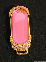 Front view of the gold-tone brooch with a large pink rectangular stone and pink rhinestone accents.